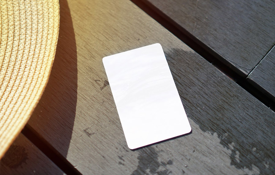 Don't forget your pool pass to to take a refreshing swim at Harmony Apartment Homes. Summer hat and key card on a deck floor.